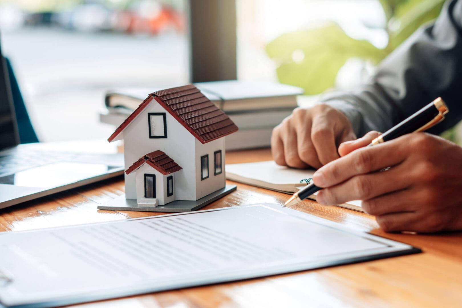 Person signing documents next to small house