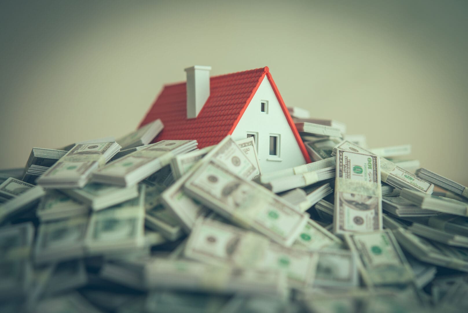 Miniature house surrounded by dollar bills