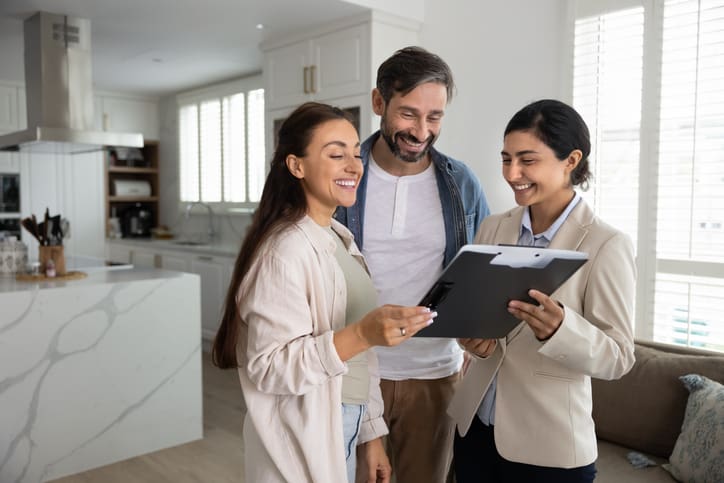 Real estate agent showing home details to a couple inside a house.