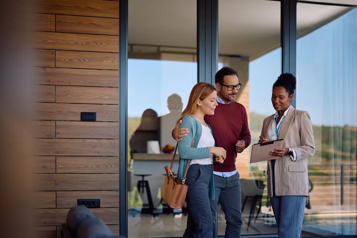 Three colleagues discussing work while standing near an office entrance.