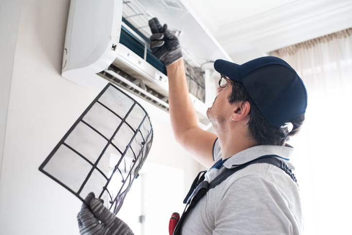 Technician cleaning an air conditioner filter during maintenance.