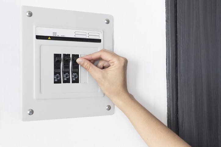 A hand adjusting circuit breakers in an electrical panel.