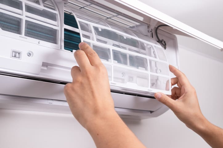 Person cleaning the filter of an air conditioning unit.