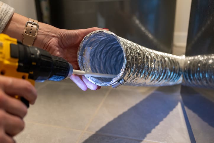 Person holding a flexible silver duct pipe.