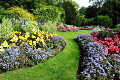 A vibrant garden with a colorful flower beds and lush green grass.