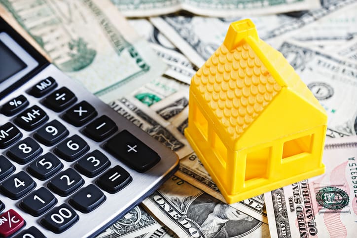 Calculator, toy house, and dollar bills