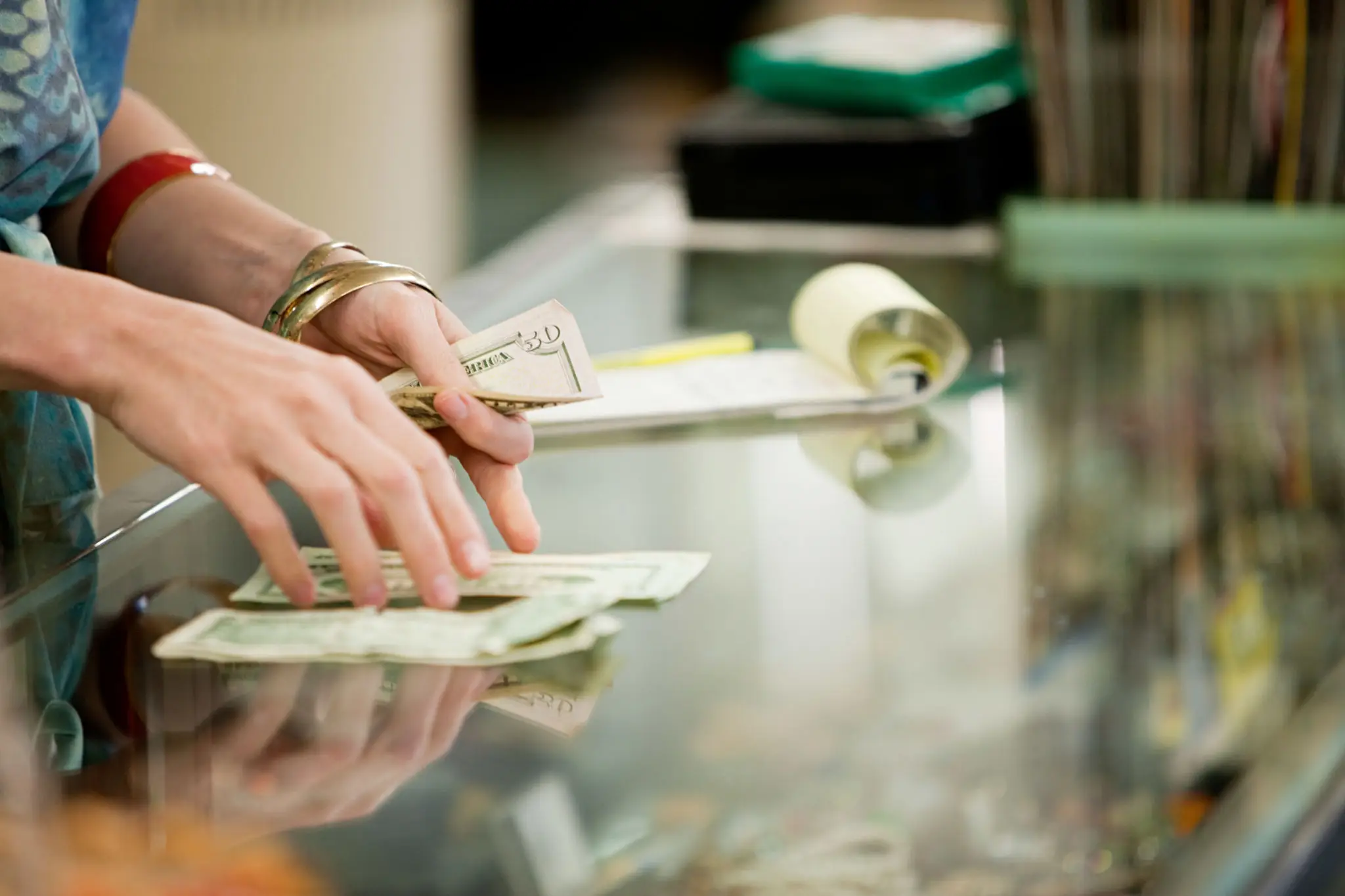 Hands counting US dollar bills on glass counter