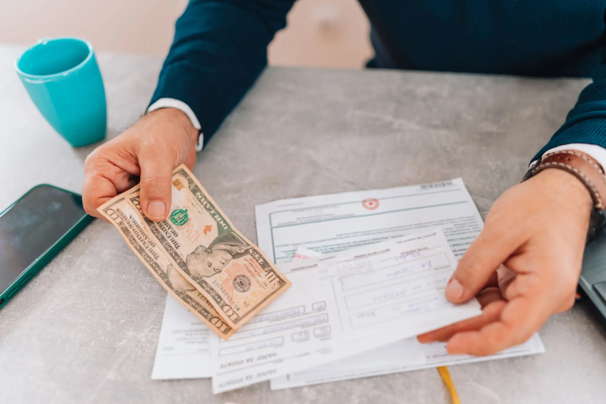 Person handing cash while filling paperwork