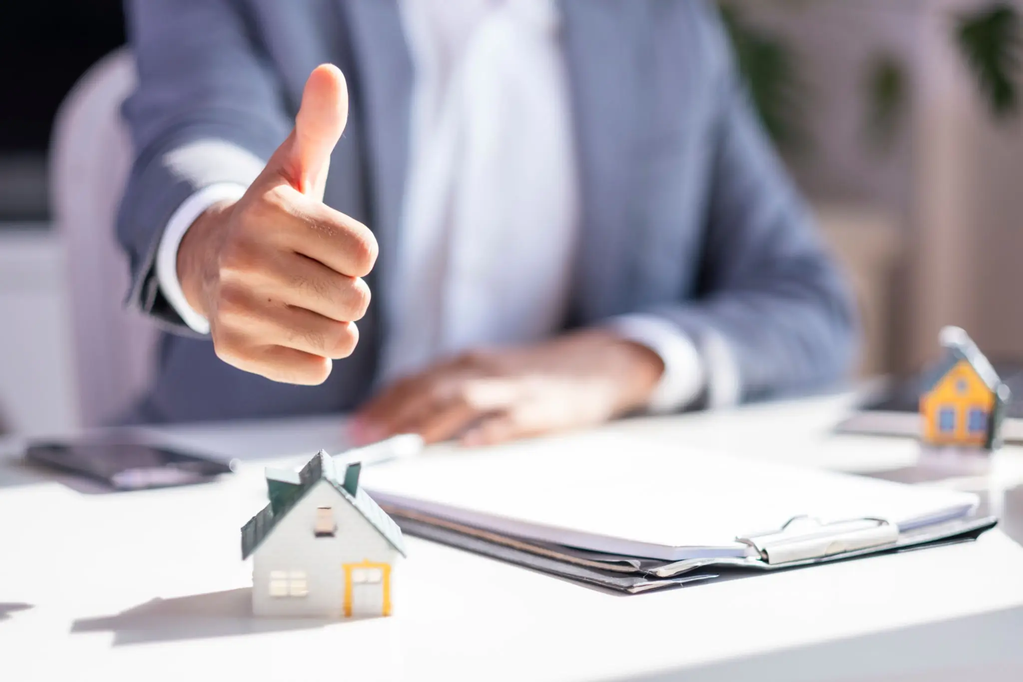 Businessperson thumbs up over model house