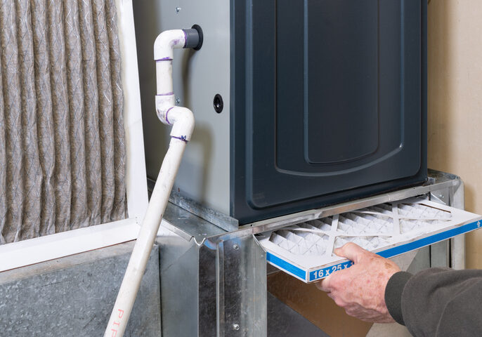 Person applying sealant to a pipe joint near a wall corner.