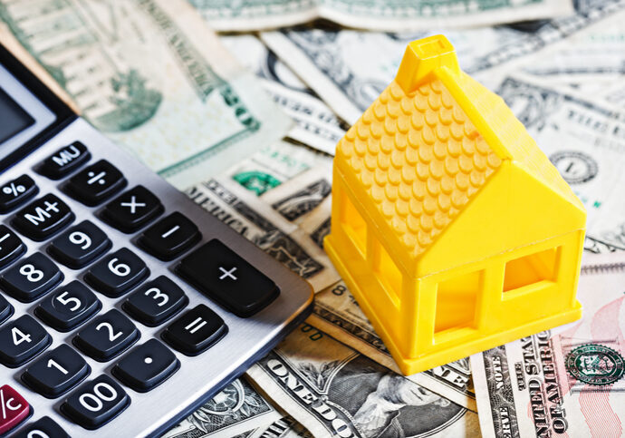 Calculator, toy house, and dollar bills