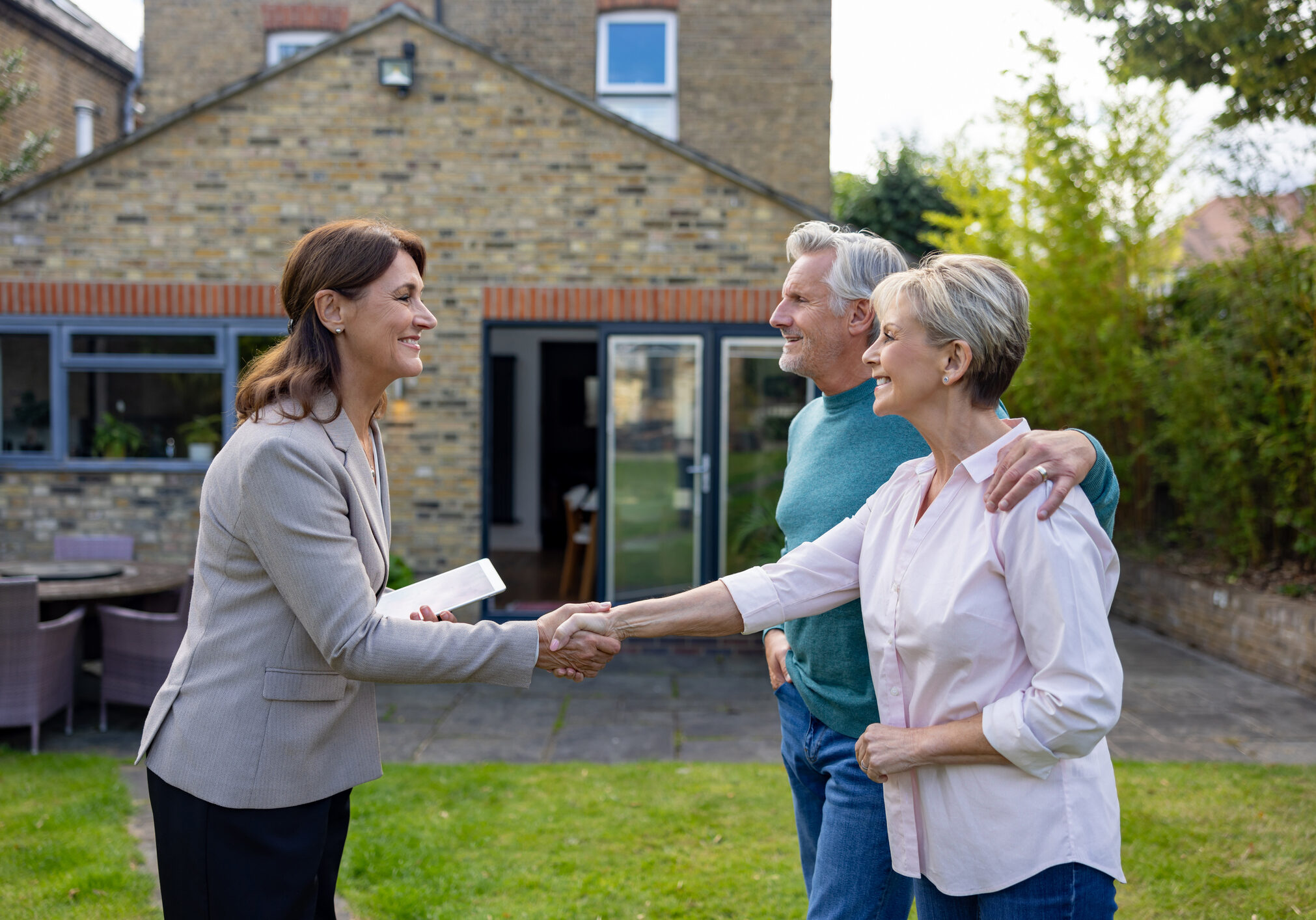 Homebuyers shaking hands with realtor.