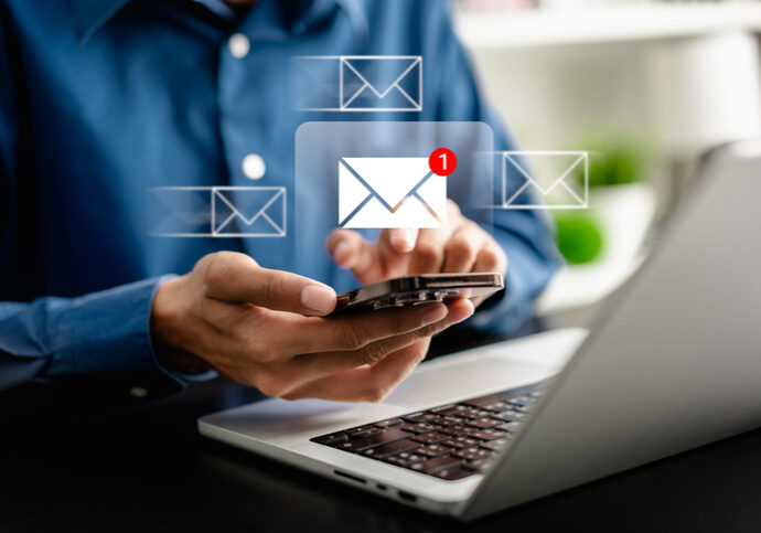 Person holding phone with email notification icons above.
