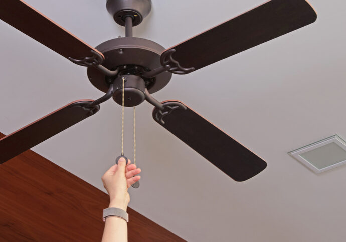 Hand pulling the cord of a ceiling fan.