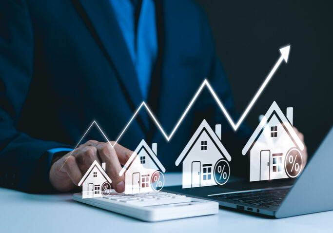 Person interacting with virtual house icons and rising graph on a tablet.