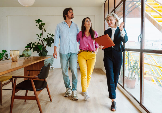 Three professionals walking and discussing in a modern office.