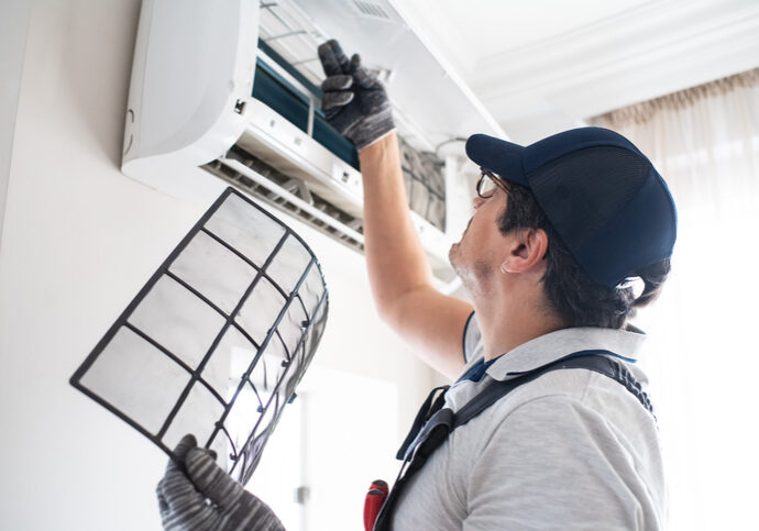 Technician cleaning an air conditioner filter during maintenance.