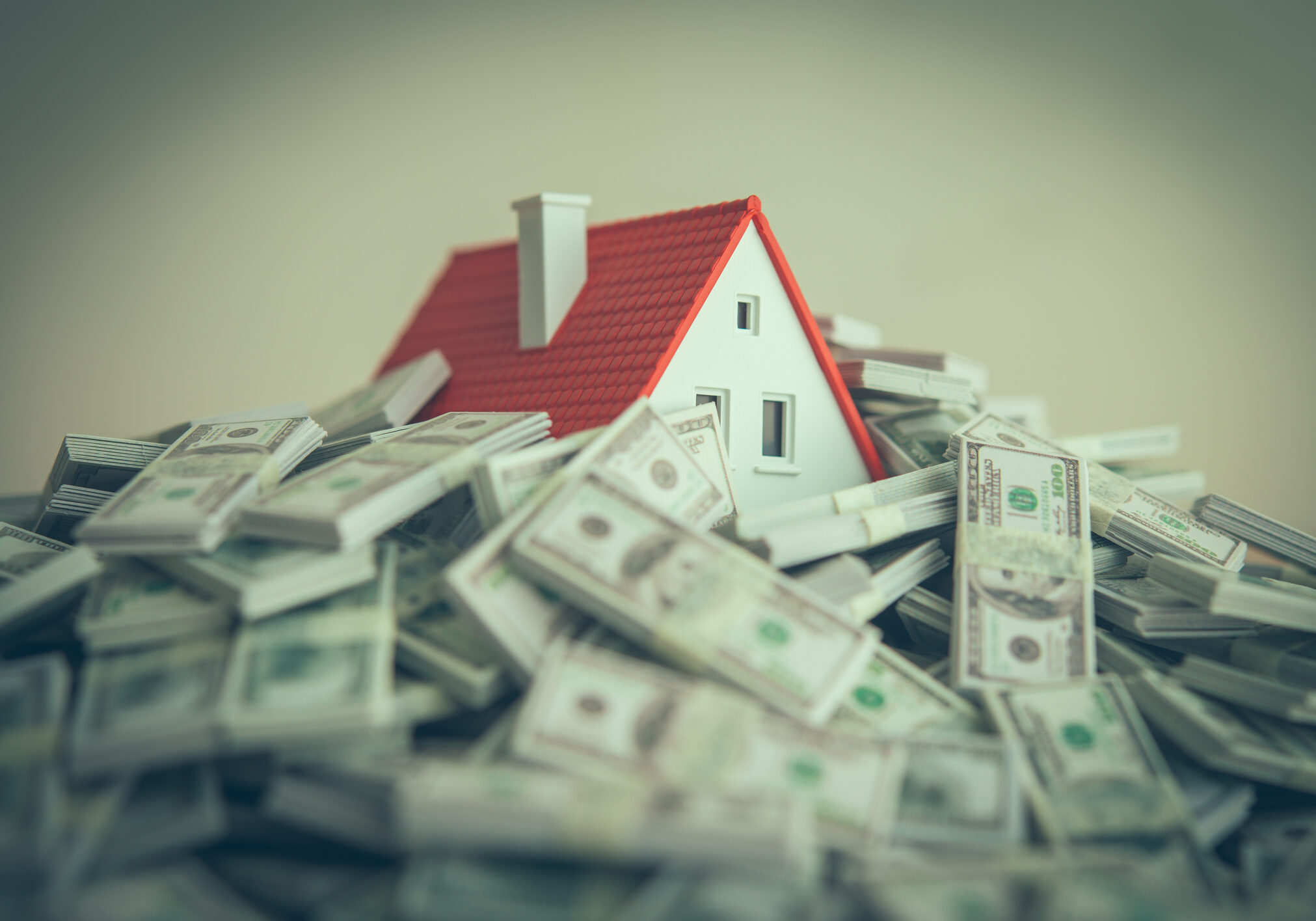 Miniature house surrounded by dollar bills