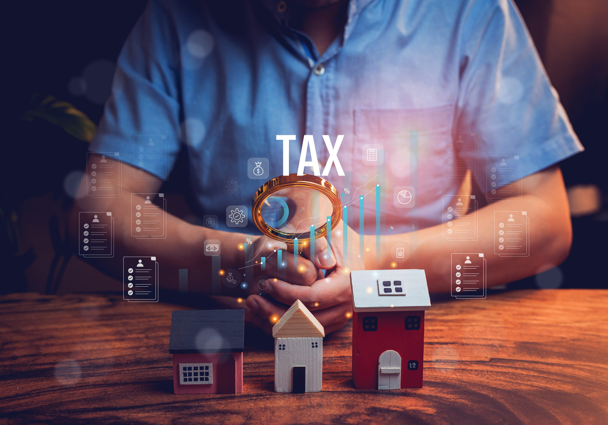 Tax concept with miniature houses and magnifying glass.