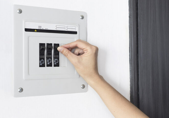 A hand adjusting circuit breakers in an electrical panel.