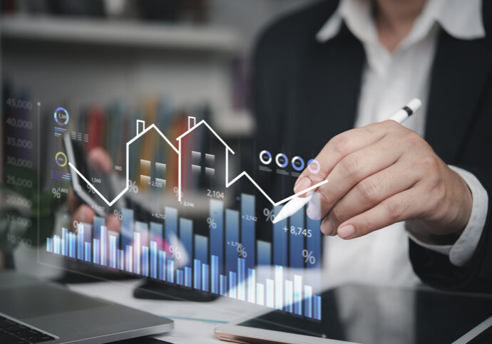 Businessman analyzing digital financial charts with house icons.