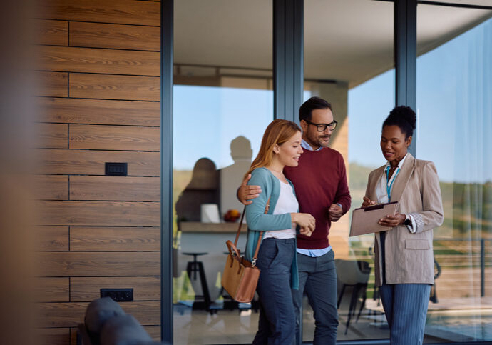 Three colleagues discussing work while standing near an office entrance.