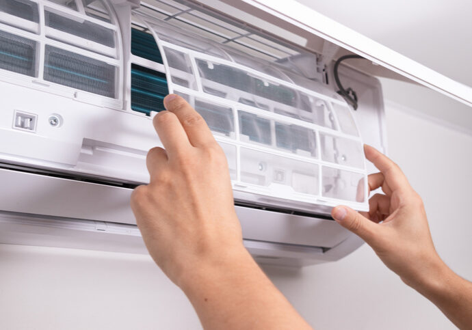 Person cleaning the filter of an air conditioning unit.