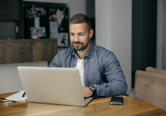 Man working on a laptop at a wooden table.