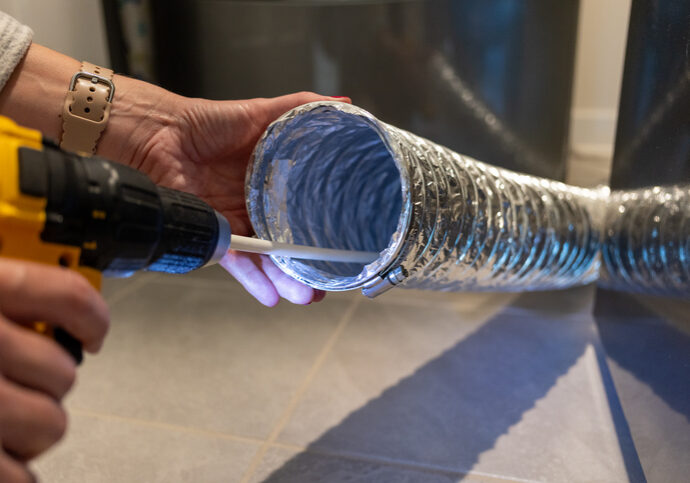 Person holding a flexible silver duct pipe.