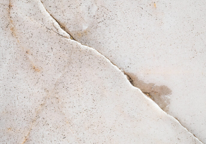 Close-up of cracked, textured white surface with subtle stains.