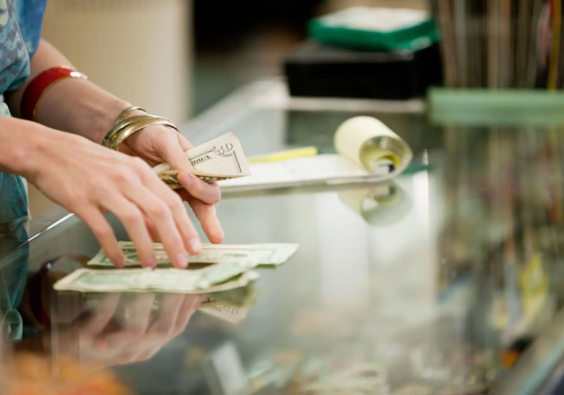 Hands counting US dollar bills on glass counter