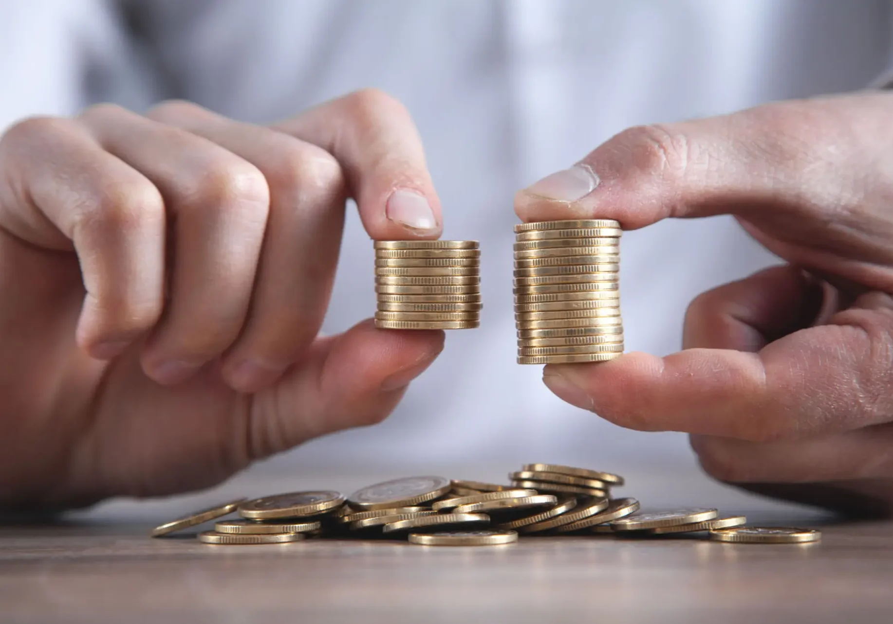 Hands comparing two stacks of coins
