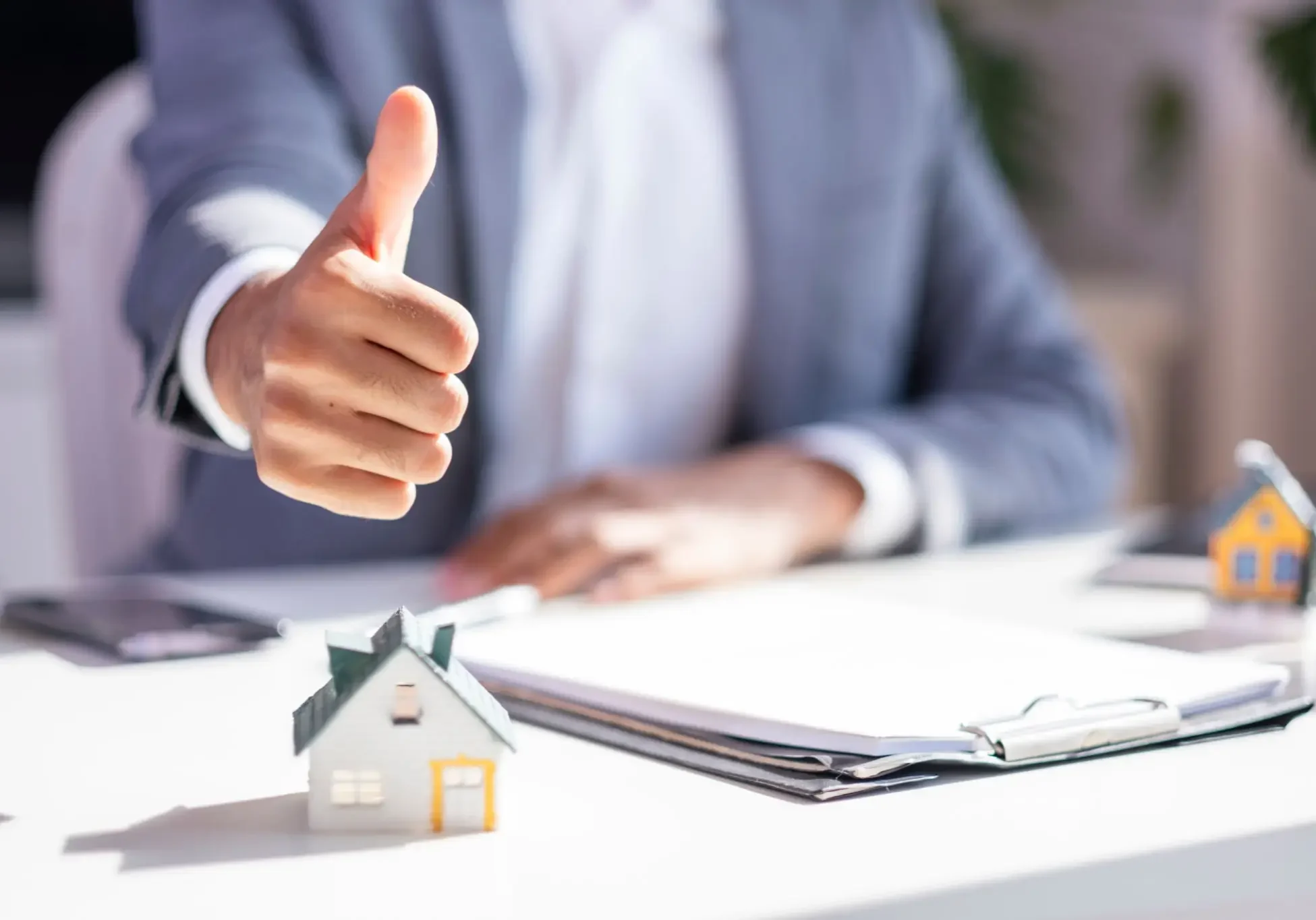 Businessperson thumbs up over model house