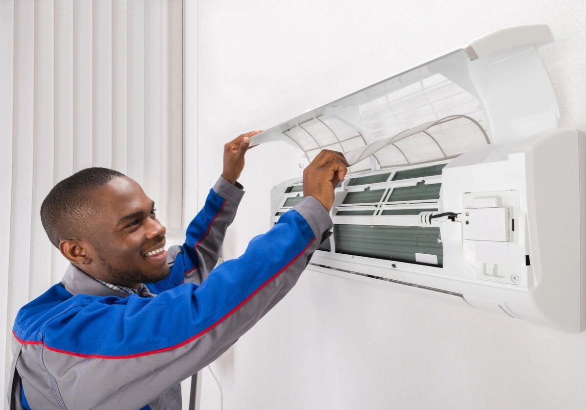 Technician installing or repairing a wall-mounted air conditioner indoors.