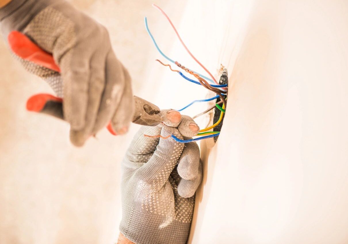 Electrician fixing electrical wires inside a wall.