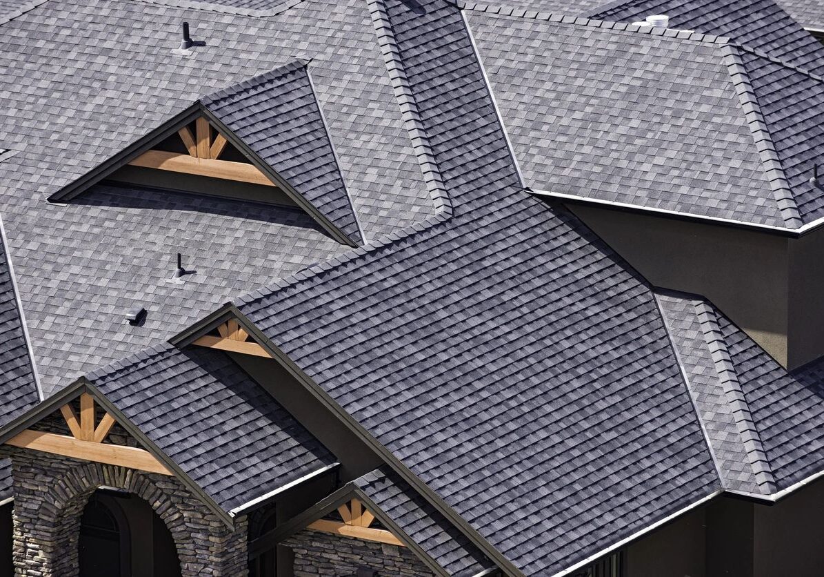 Close-up aerial view of a complex residential roof with gray shingles.
