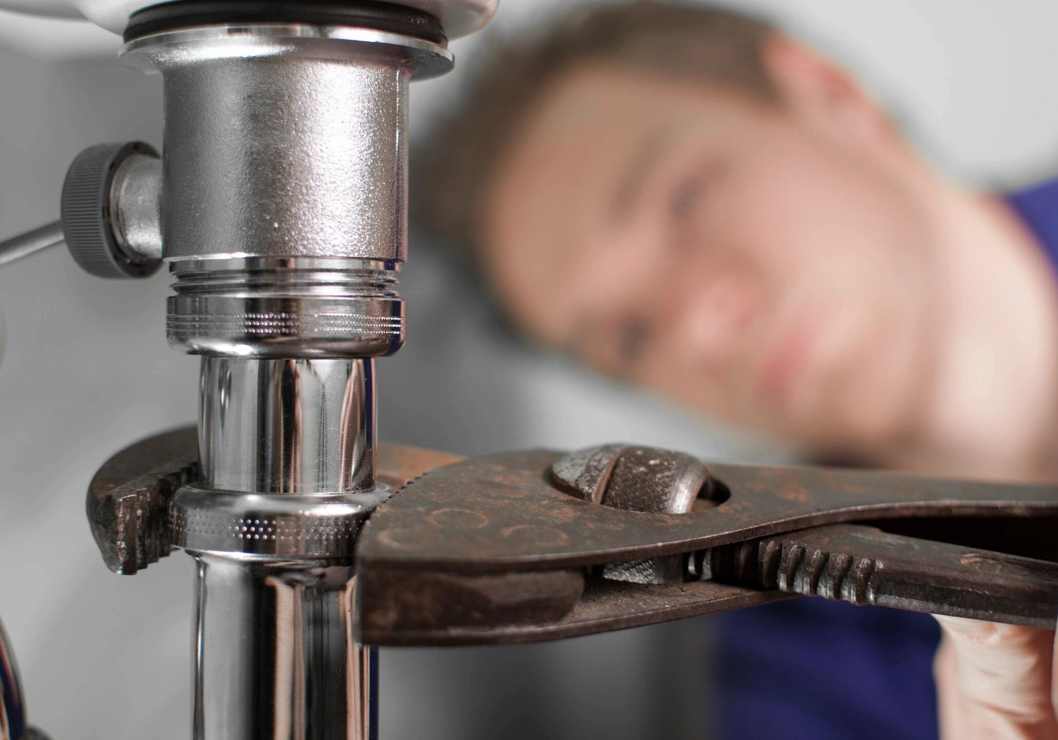 A person using a wrench to fix a metal pipe.