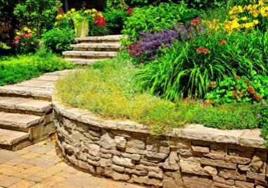 Stone retaining wall with a lush garden and stone steps.