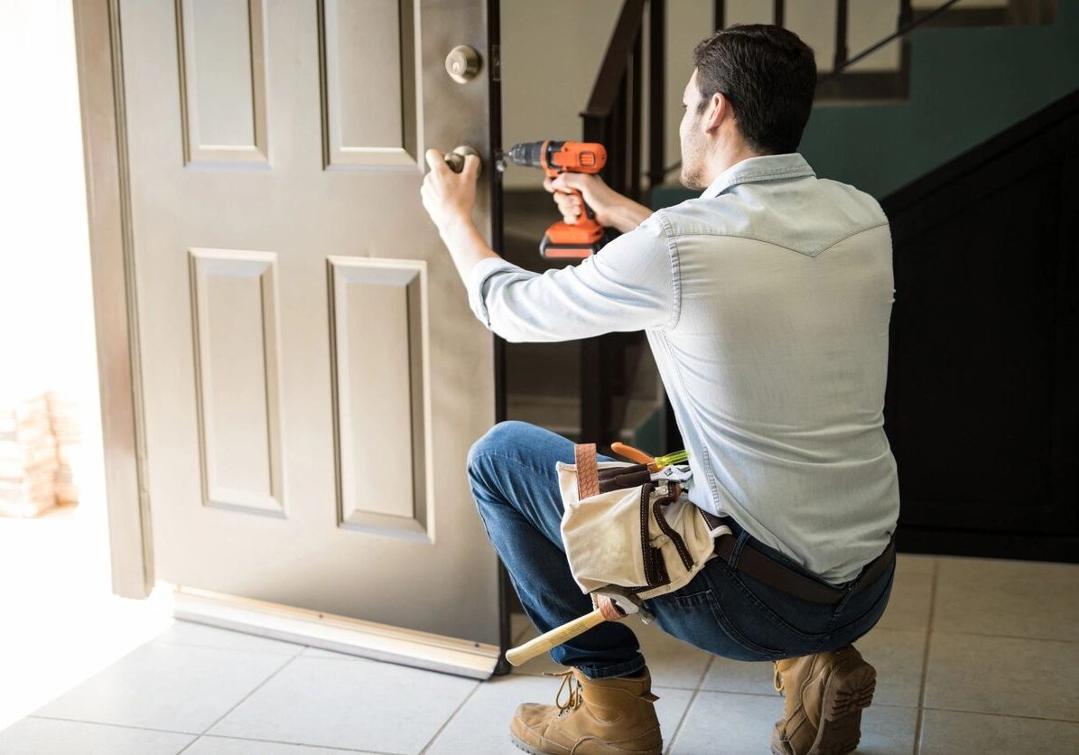 Man installing a door handle using an electric screwdriver.