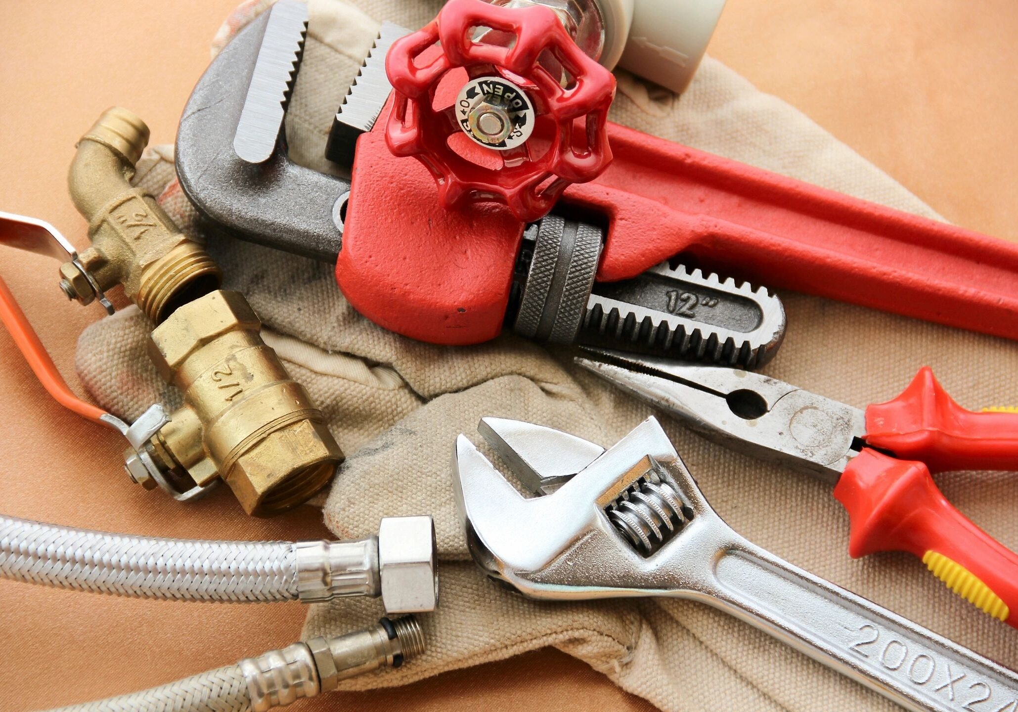 A set of plumbing tools including wrenches and a red valve handle.