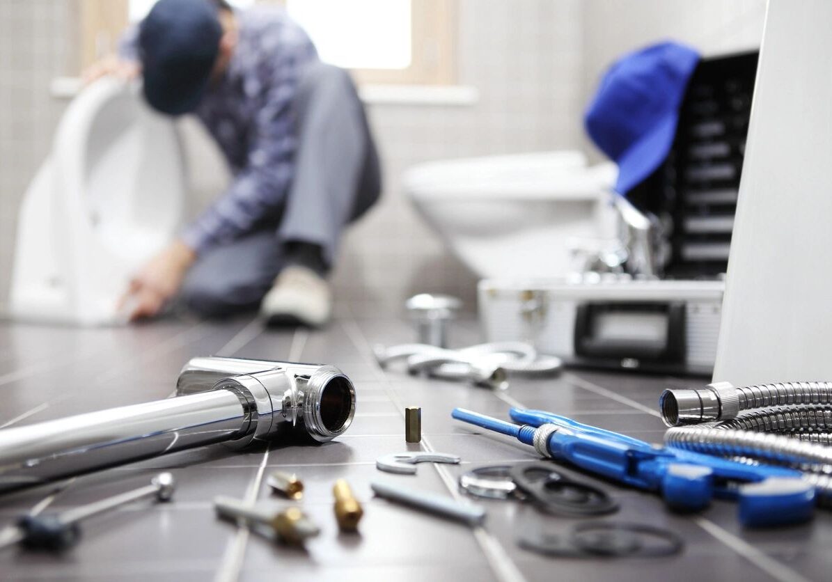 Close-up of plumbing tools and a plumber working in the background.