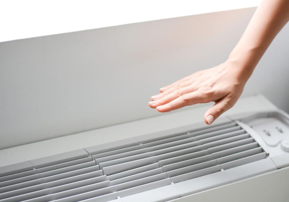 Hand warming near a heater vent.