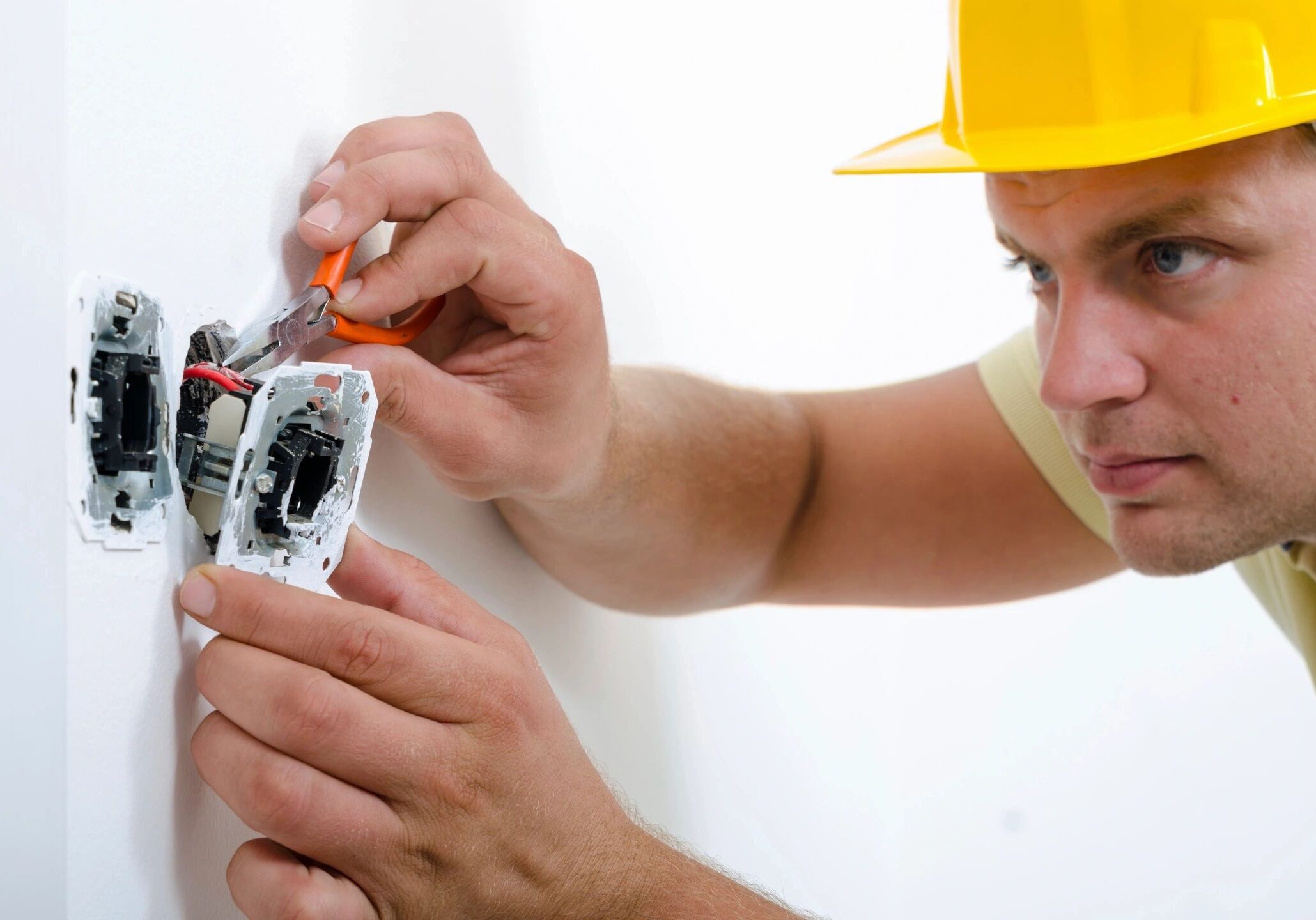 Electrician repairing a wall socket with a screwdriver.