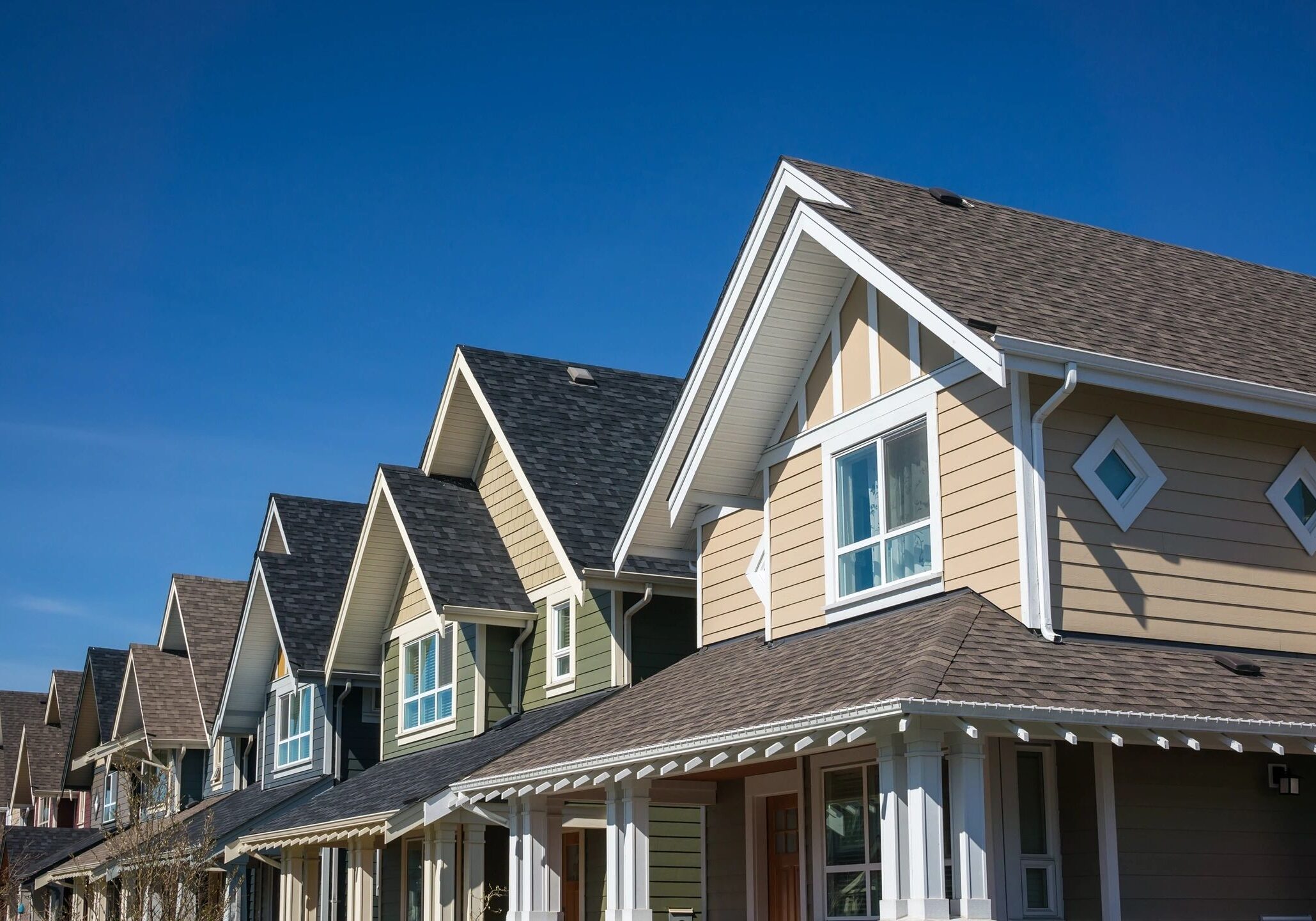 Row of modern suburban houses under clear blue sky.