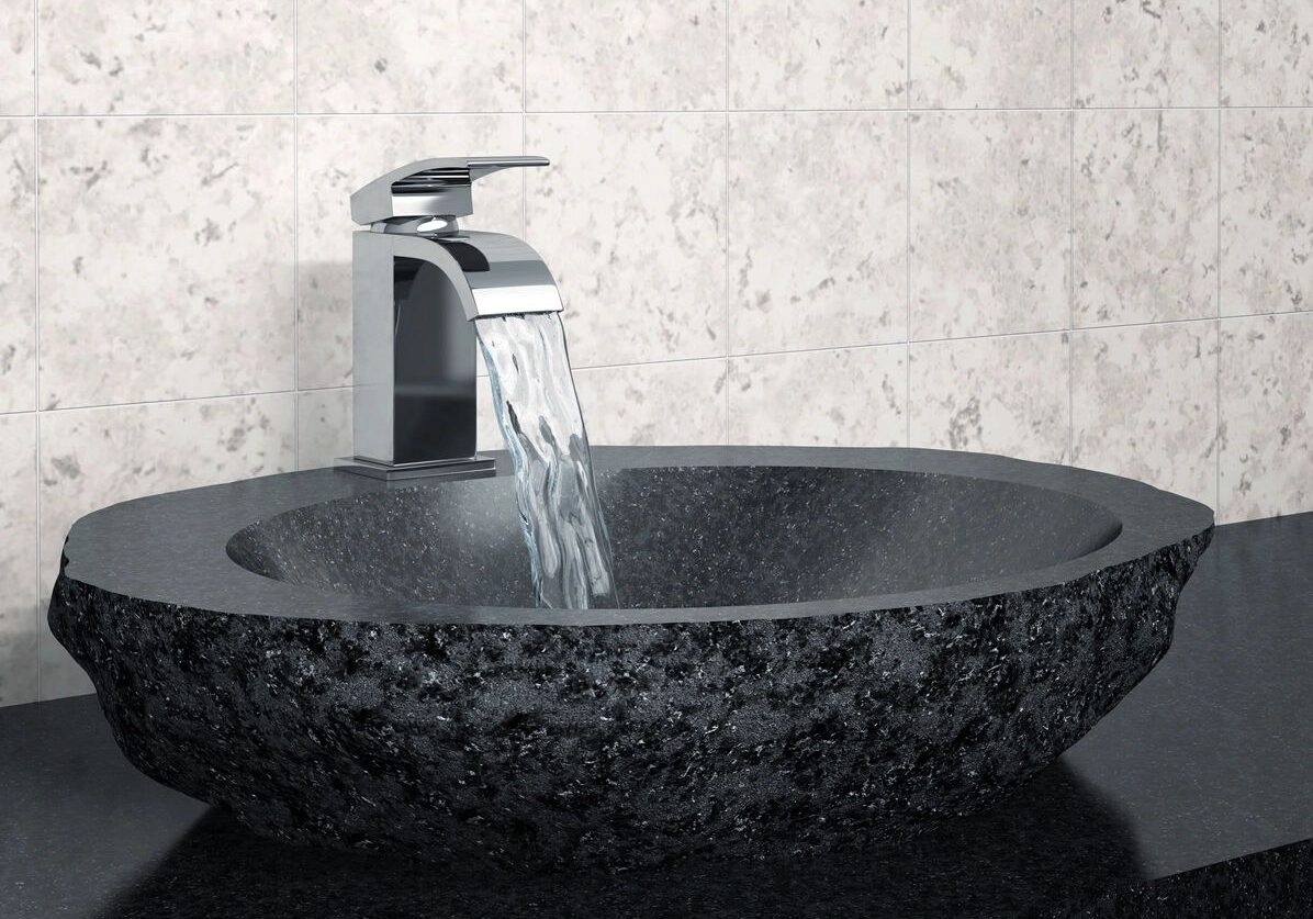 Modern black stone sink with flowing water from a sleek faucet.