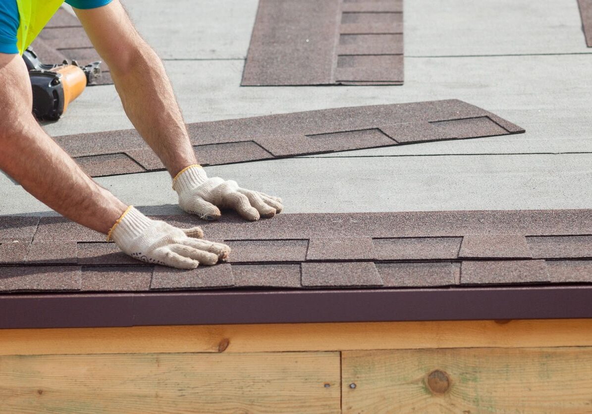 Worker installing asphalt shingles on a roof.
